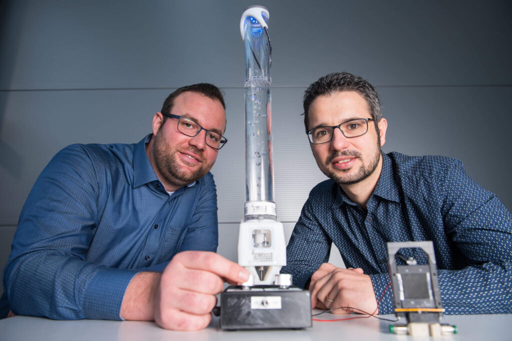 Die Ingenieure Philipp Linnebach (l.) und Steffen Hau (r.) aus dem Forscherteam von Stefan Seelecke mit Prototypen einer motorlosen Pumpe (Mitte) und eines smarten Ventils (vorne rechts) aus Folie.